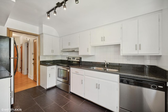 kitchen with under cabinet range hood, a sink, white cabinetry, appliances with stainless steel finishes, and decorative backsplash