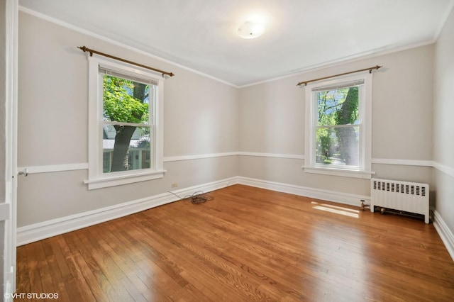 spare room featuring radiator, wood-type flooring, ornamental molding, and baseboards