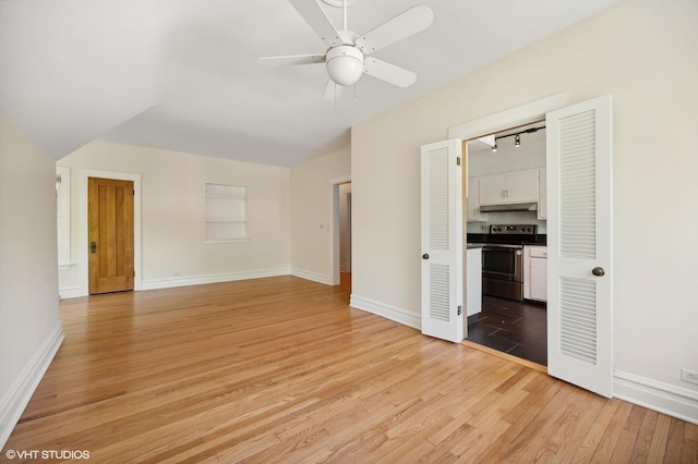 empty room featuring light wood finished floors, a ceiling fan, and baseboards