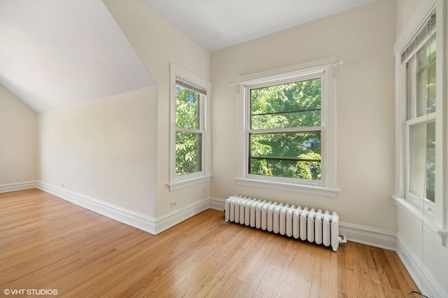 additional living space with lofted ceiling, radiator heating unit, baseboards, and wood-type flooring