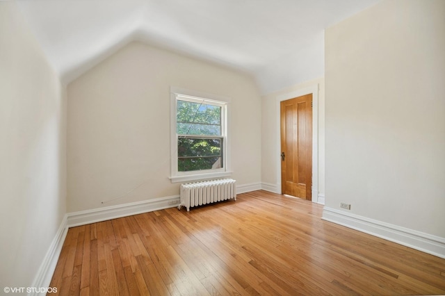 additional living space with light wood-style floors, radiator heating unit, baseboards, and vaulted ceiling