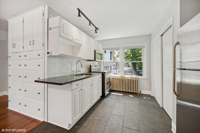 kitchen featuring tasteful backsplash, white cabinets, radiator heating unit, appliances with stainless steel finishes, and a sink