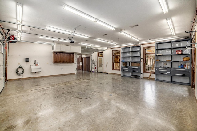 garage with baseboards, visible vents, a sink, and a garage door opener