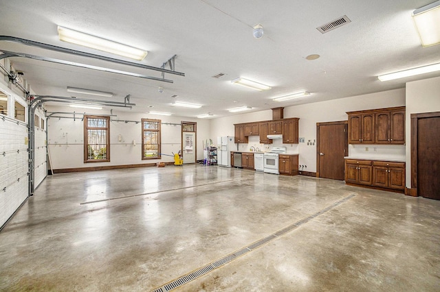 garage with baseboards, white refrigerator with ice dispenser, and visible vents