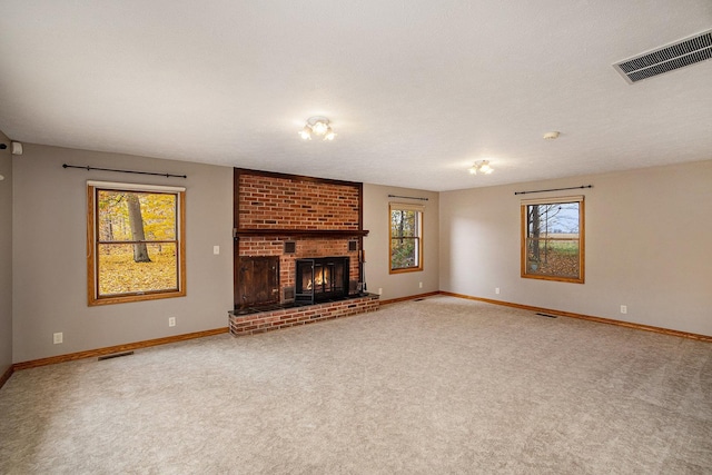 unfurnished living room with carpet floors, a brick fireplace, baseboards, and visible vents