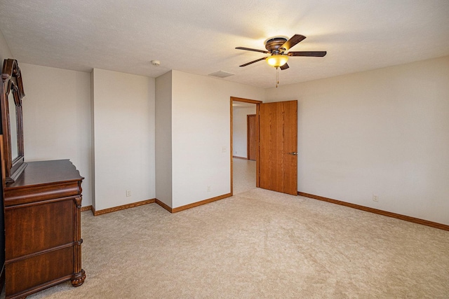 unfurnished room featuring baseboards, visible vents, light colored carpet, ceiling fan, and a textured ceiling