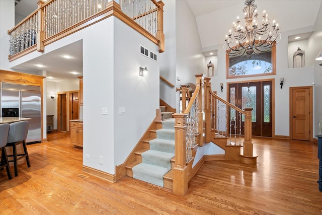 foyer entrance featuring an inviting chandelier, light hardwood / wood-style flooring, and a high ceiling