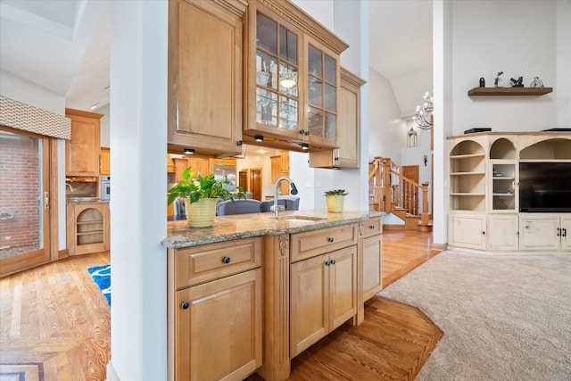 kitchen with light hardwood / wood-style floors, light brown cabinetry, light stone countertops, and sink