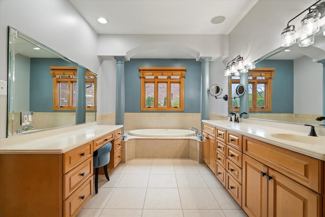 bathroom with ornate columns, vanity, tile patterned flooring, and tiled bath