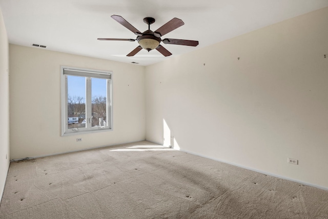 spare room with ceiling fan, visible vents, and light colored carpet