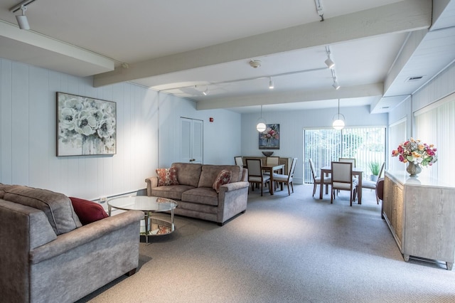 living area with carpet, visible vents, beamed ceiling, and track lighting