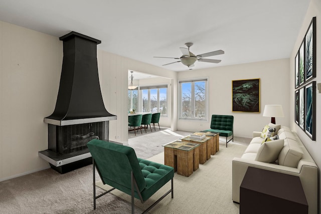 living area featuring a ceiling fan, a wood stove, and light colored carpet