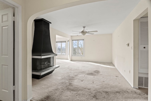 unfurnished living room with light carpet and a ceiling fan