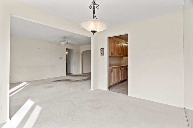 interior space with arched walkways, light colored carpet, and ceiling fan