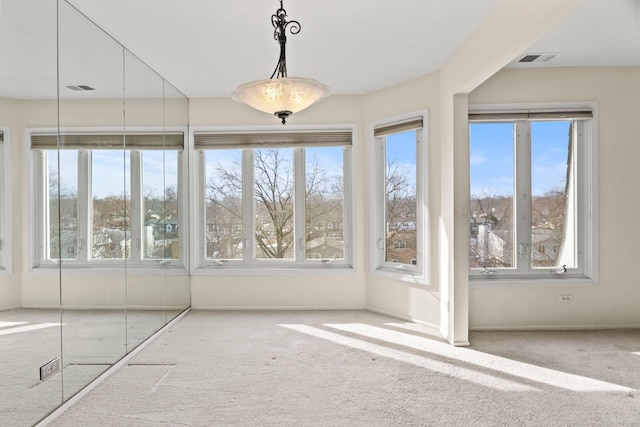 unfurnished dining area with light carpet, visible vents, and baseboards