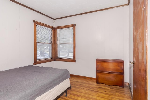bedroom featuring crown molding and light hardwood / wood-style flooring