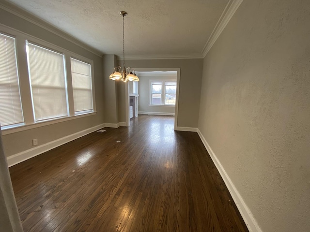 unfurnished dining area with crown molding, dark hardwood / wood-style flooring, a chandelier, and a textured ceiling