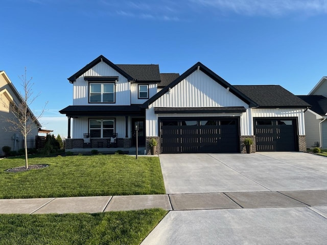 view of front of home with brick siding, board and batten siding, a front yard, a garage, and driveway