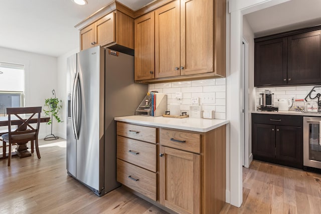 kitchen featuring stainless steel fridge, beverage cooler, decorative backsplash, light wood-style flooring, and light countertops