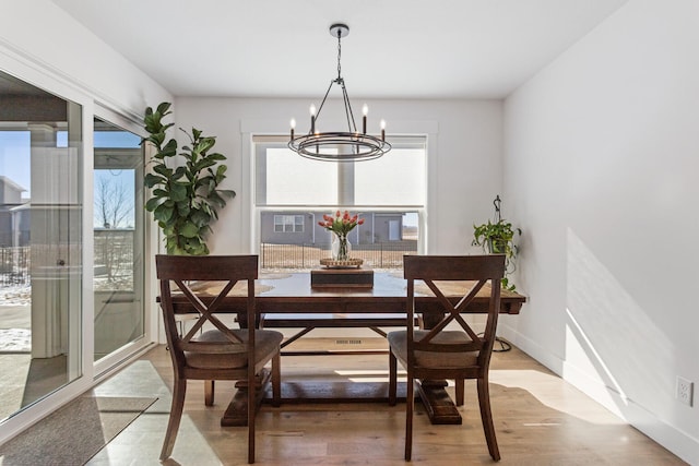 dining space featuring baseboards, wood finished floors, and an inviting chandelier