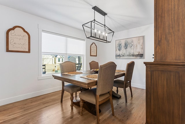 dining room with a chandelier, baseboards, and wood finished floors