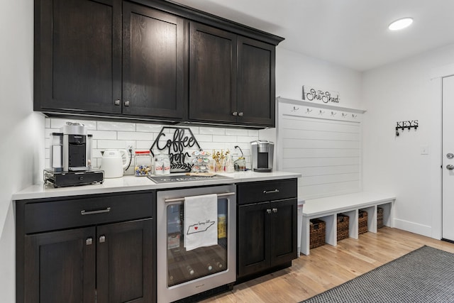 bar with beverage cooler, light wood-style flooring, and decorative backsplash