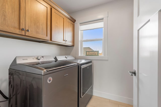 laundry area with cabinet space, baseboards, washer and dryer, and light tile patterned flooring