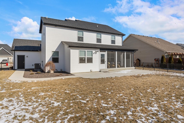 snow covered house featuring central air condition unit, a patio area, fence, and a sunroom