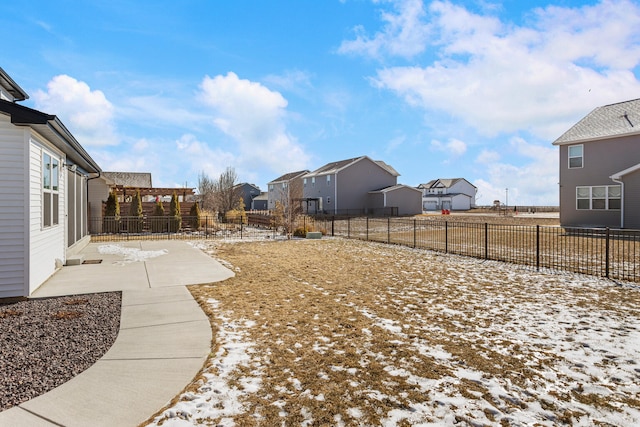 yard layered in snow with a patio, a fenced backyard, and a residential view