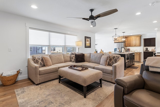 living area with light wood-type flooring, ceiling fan, baseboards, and recessed lighting