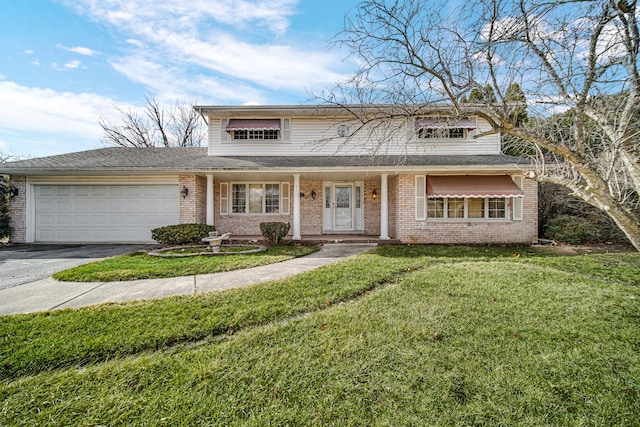 traditional-style home with a garage, aphalt driveway, a front yard, and brick siding