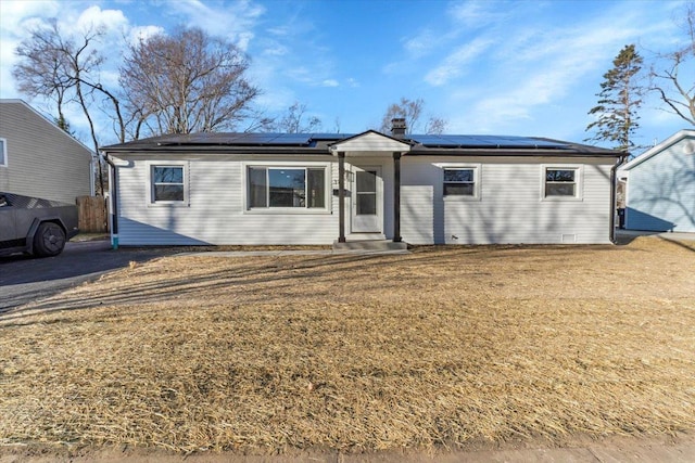 ranch-style home with a front yard and solar panels