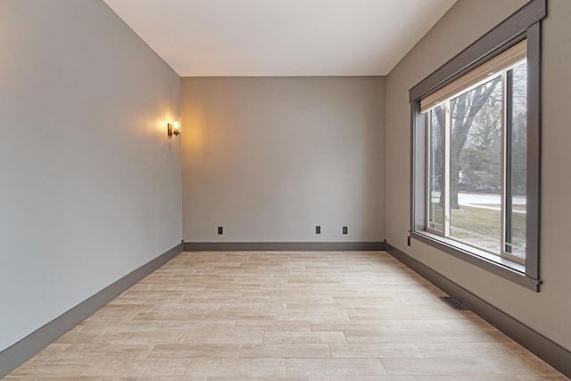 unfurnished room featuring visible vents, light wood-style flooring, and baseboards