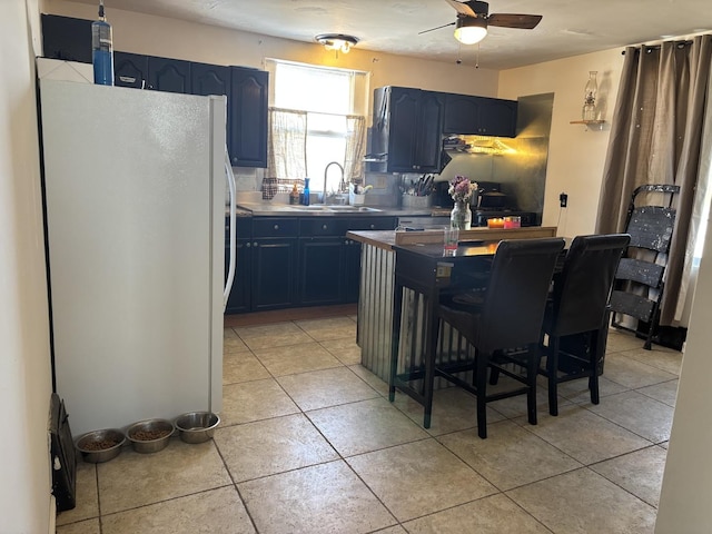 kitchen featuring stove, a sink, freestanding refrigerator, and blue cabinets