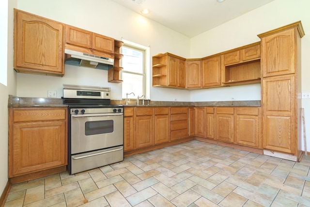 kitchen featuring under cabinet range hood, stainless steel range oven, open shelves, brown cabinetry, and dark countertops