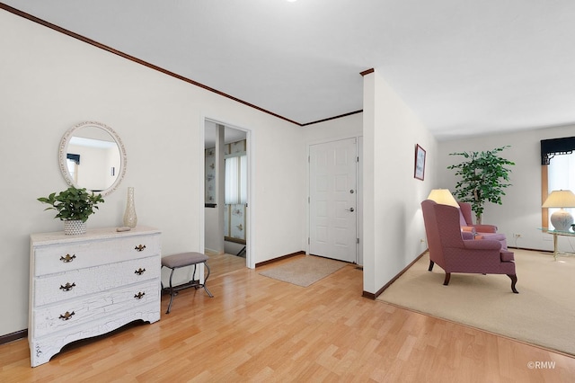 sitting room with ornamental molding, light wood-style flooring, and baseboards