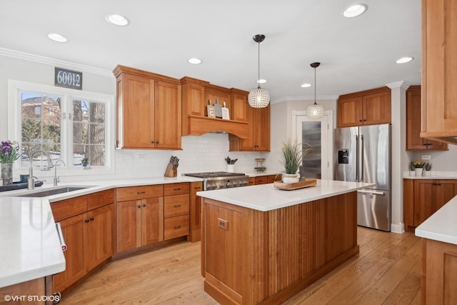 kitchen with a sink, a kitchen island, high end fridge, hanging light fixtures, and light countertops