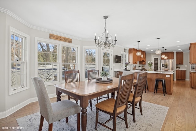 dining space with a notable chandelier, crown molding, light wood-style flooring, and baseboards