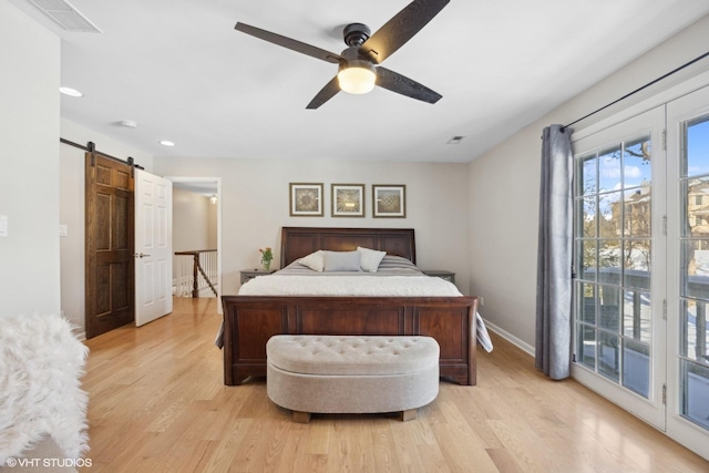 bedroom featuring light wood-style floors, a barn door, visible vents, and access to outside