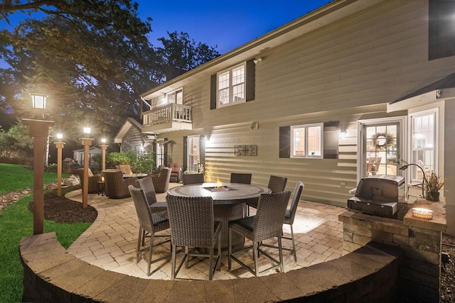 view of patio with an outdoor fire pit, a balcony, and outdoor dining space