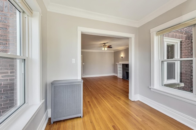 unfurnished living room with crown molding, a wealth of natural light, and light hardwood / wood-style floors