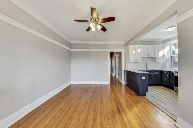 kitchen featuring white cabinetry, crown molding, light wood-type flooring, ceiling fan, and decorative backsplash