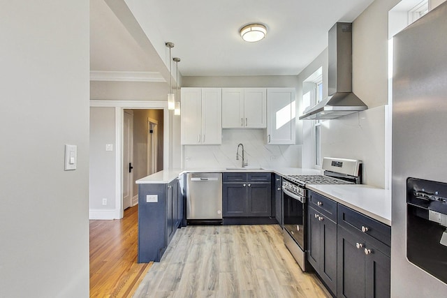 kitchen featuring wall chimney exhaust hood, sink, white cabinetry, hanging light fixtures, and appliances with stainless steel finishes