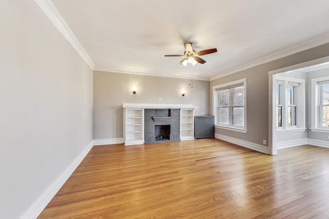 unfurnished living room featuring ornamental molding, a healthy amount of sunlight, a brick fireplace, and light hardwood / wood-style flooring