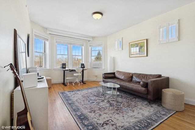 living room featuring baseboards, light wood-style floors, and cooling unit