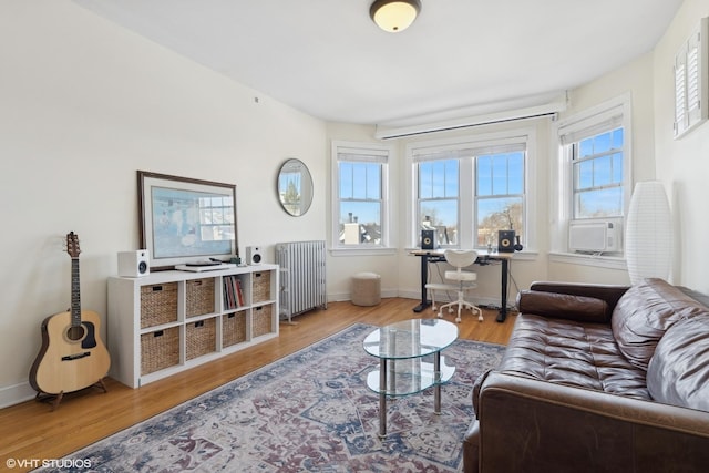 living area featuring baseboards, light wood-style floors, and radiator heating unit