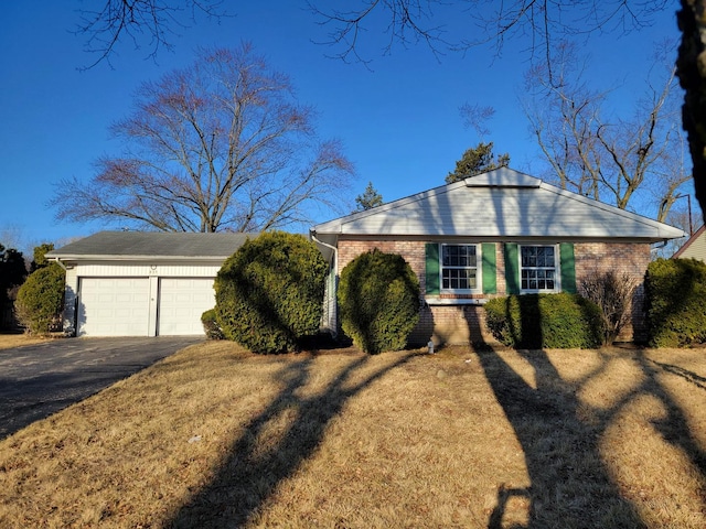 view of front of property featuring brick siding, driveway, and a front yard
