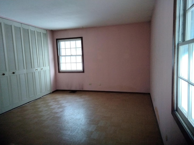 unfurnished bedroom featuring tile patterned floors, baseboards, and a closet
