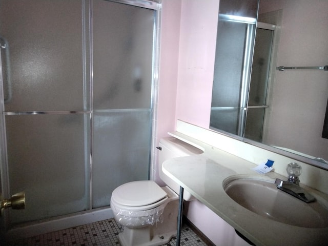bathroom featuring tile patterned floors, a stall shower, toilet, and a sink