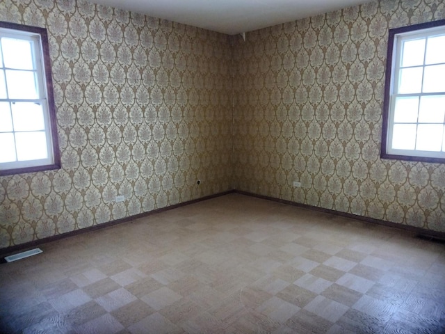 unfurnished room featuring visible vents, baseboards, and a healthy amount of sunlight